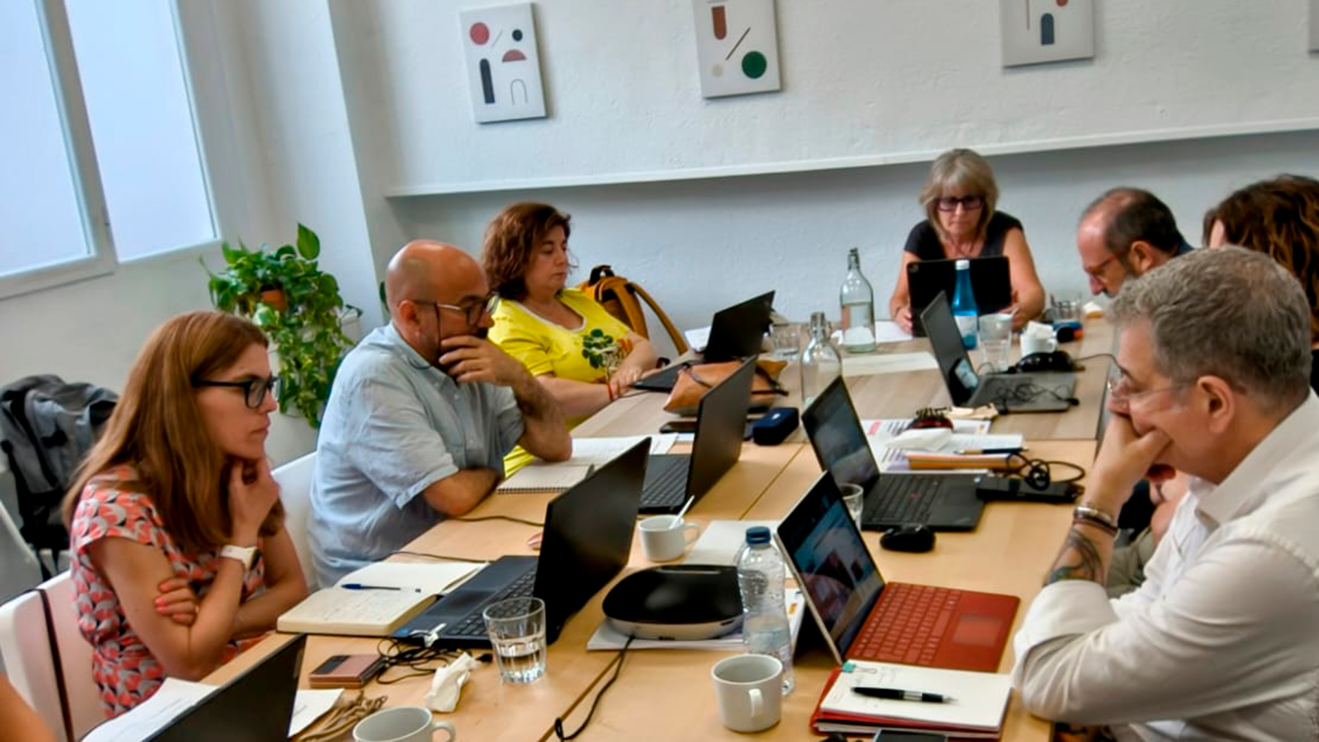 Miembros de Junta Directiva alrededor de una mesa mirando a sus portátiles.
