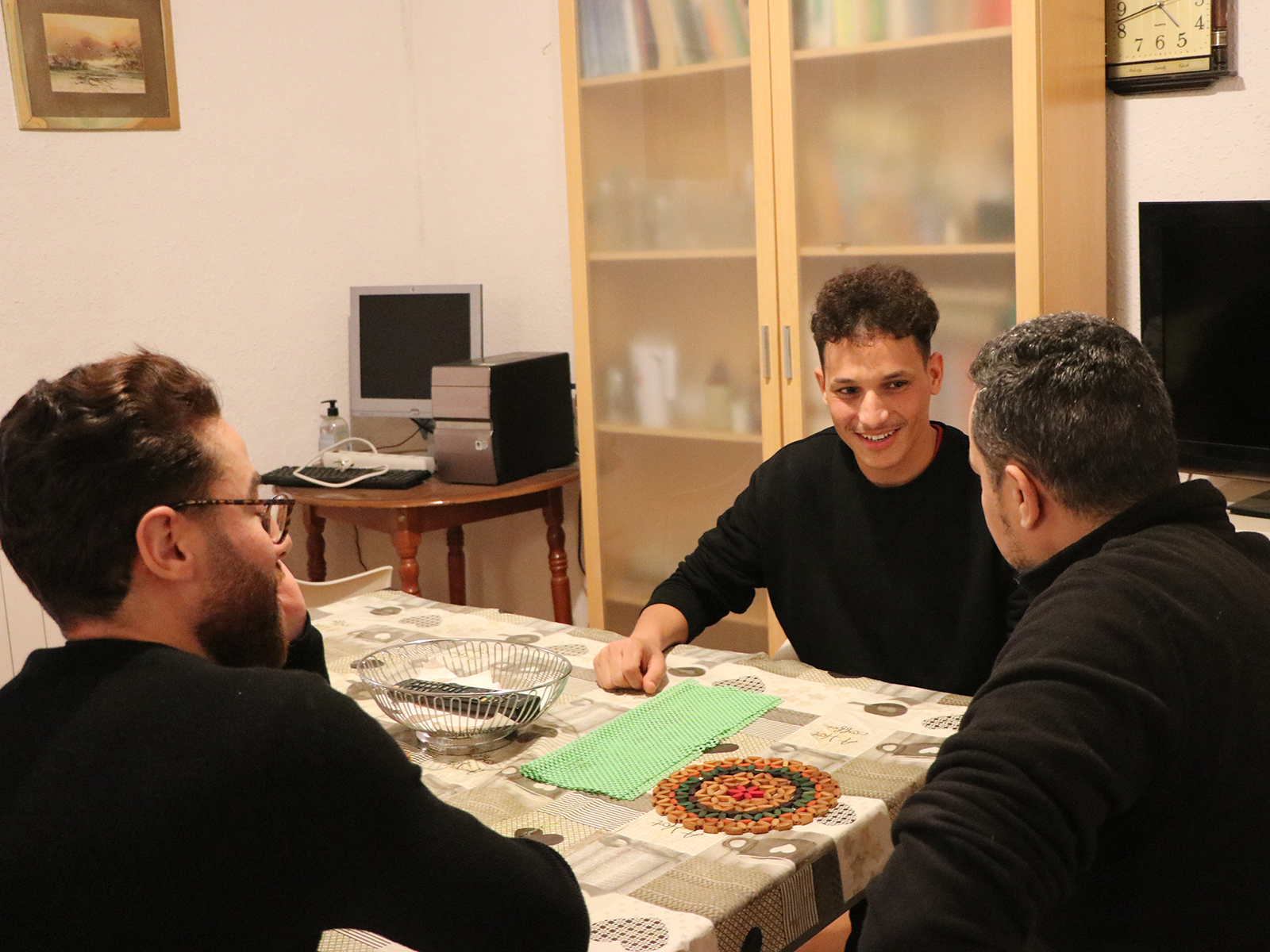 Joven extutelado vinculado a Caritas conversa con dos profesionales de la entidad.