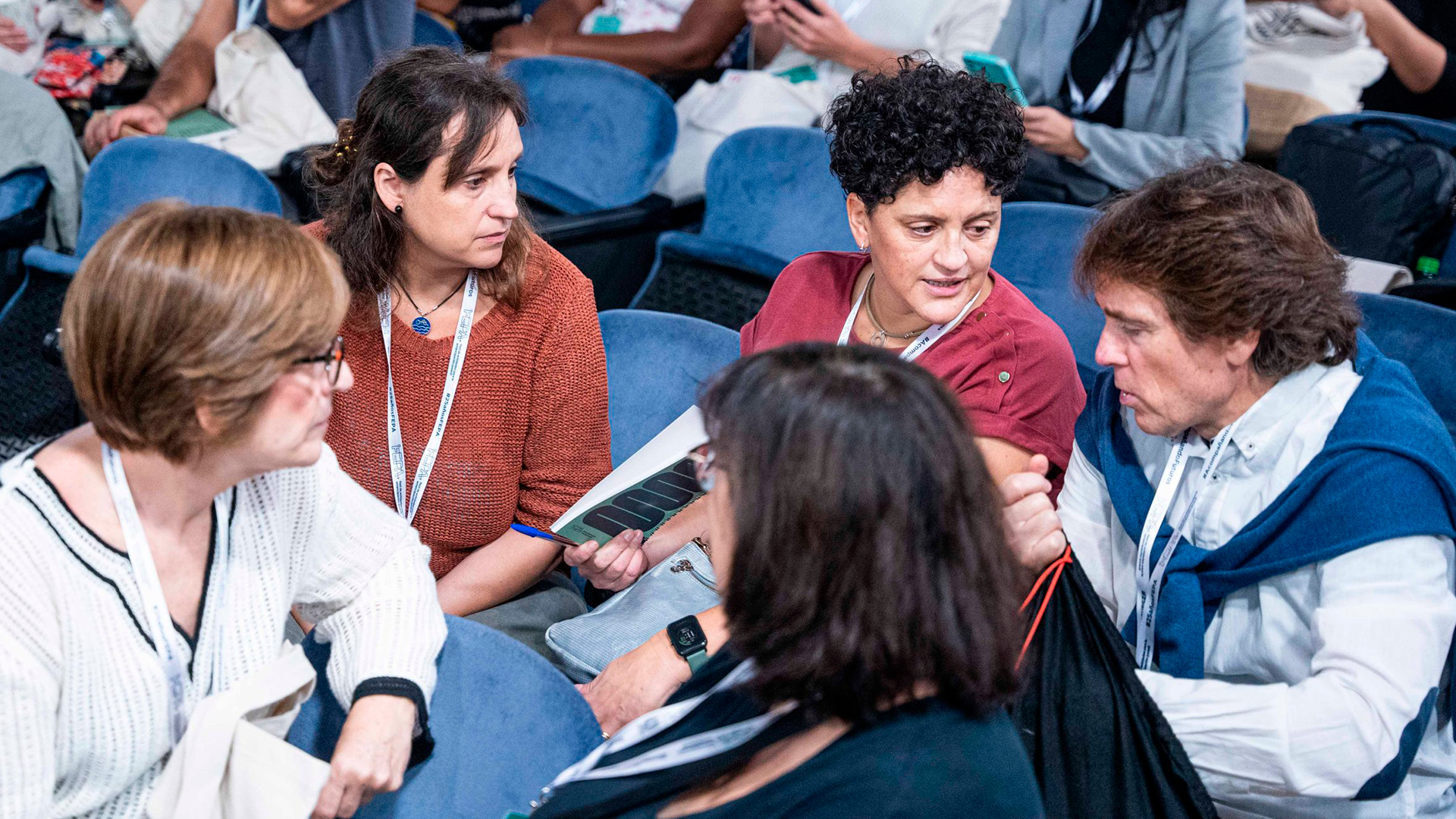 Un grupo de cinco personas, sentadas en dos filas del auditorio donde se llevaron a cabo las XVIII jornadas FEPA, conversa entre ellas, aprovechando una pausa.
