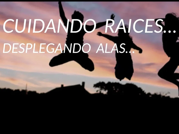 Imagen de un atardecer en la que se atisba la silueta de tres personas jóvenes saltando y se lee 'Cuidando raíces, desplegando alas'.