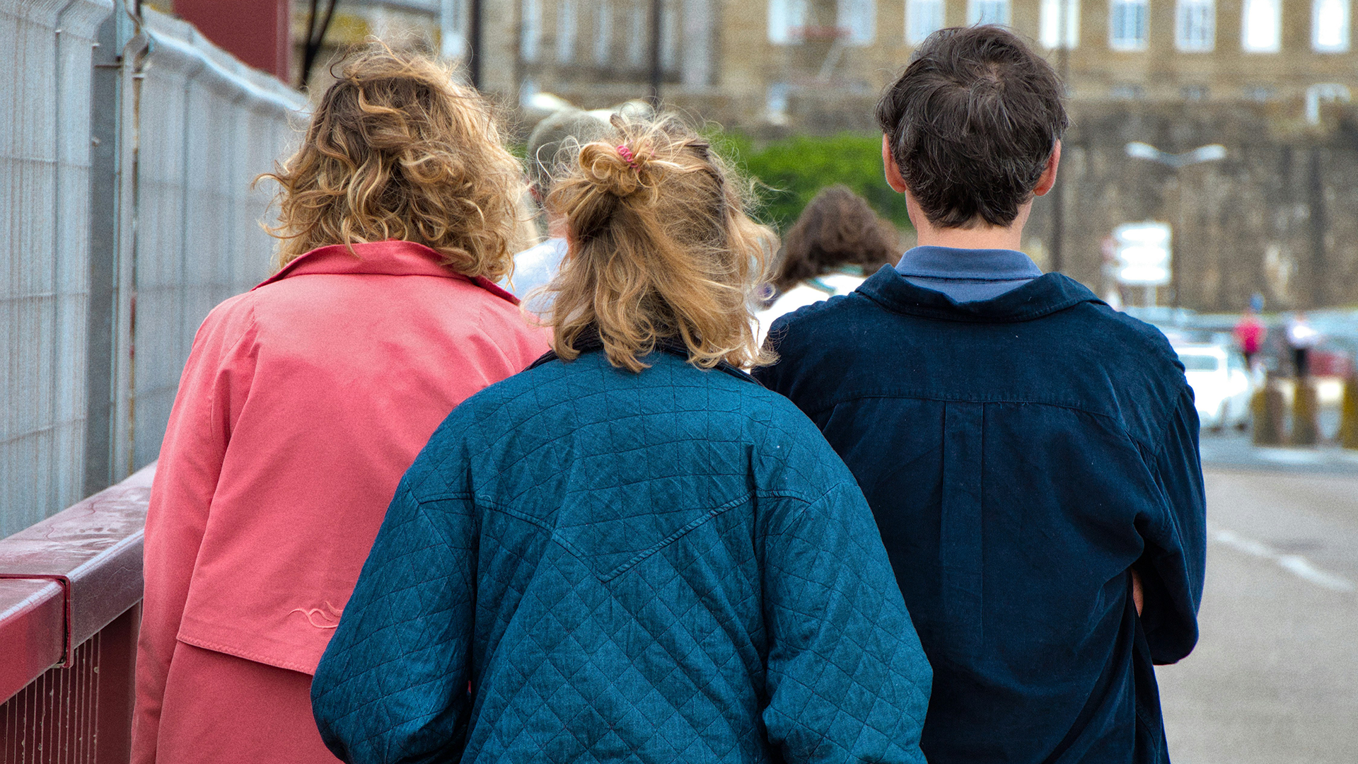 Tres chicas jóvenes de espaldas caminando en la calle.