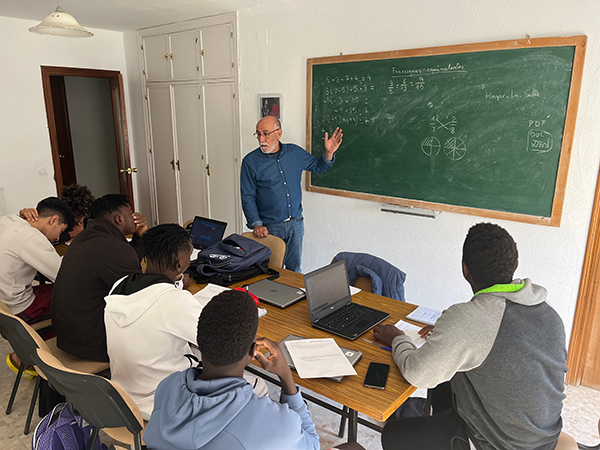 Un profesional de Hogar la Salle que imparte una clase de matemáticas para un grupo de jóvenes extutelados racializados, señala a la pizarra.