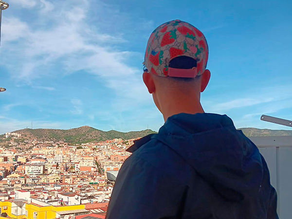 Un joven con gorra de espaldas mira hacia la montaña de Collserola en Barcelona.