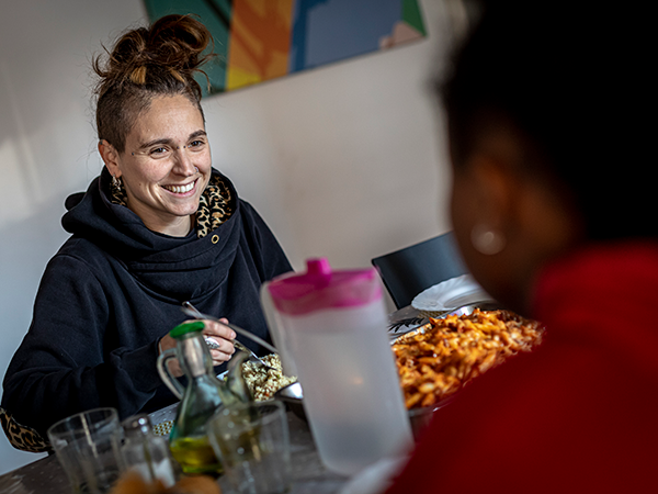 Una educadora charla, ante un plato de comida, con una joven extutelada a la que se ve de espaldas.