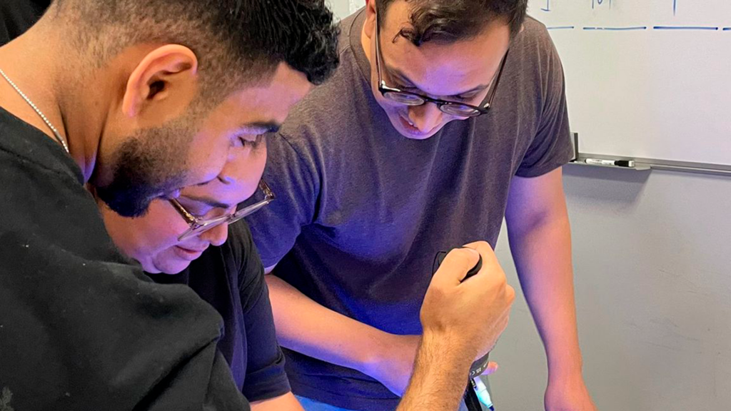 Imagen de tres chicos con una linterna durante una prueba del escape room.