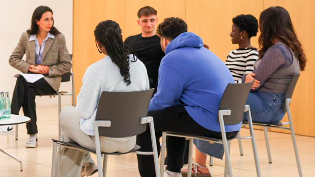 Un grupo de jóvenes extutelados, sentados en coro en un aula de la universidad Pompeu Fabra de Barcelona.