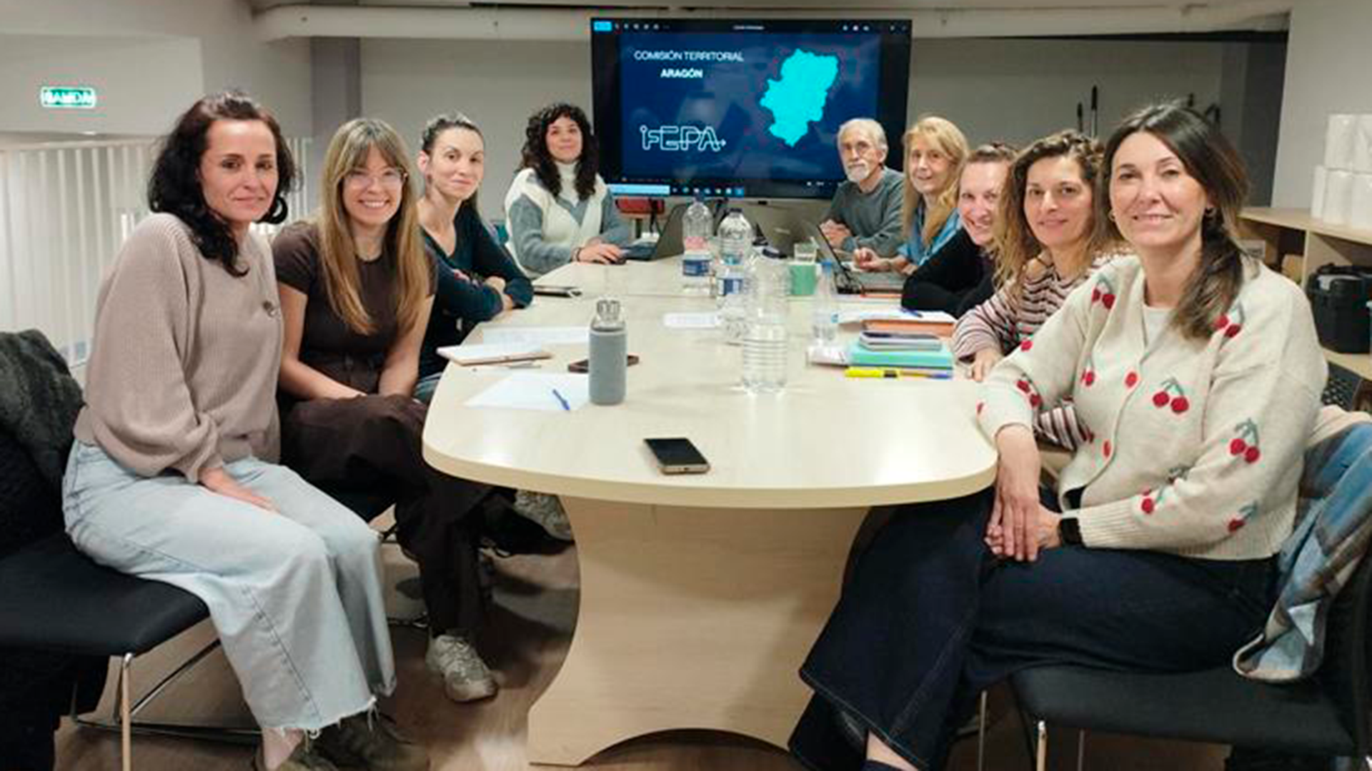 Miembros de la Comisión Territorial de Aragón reunidos alrededor de una mesa y mirando a cámara.