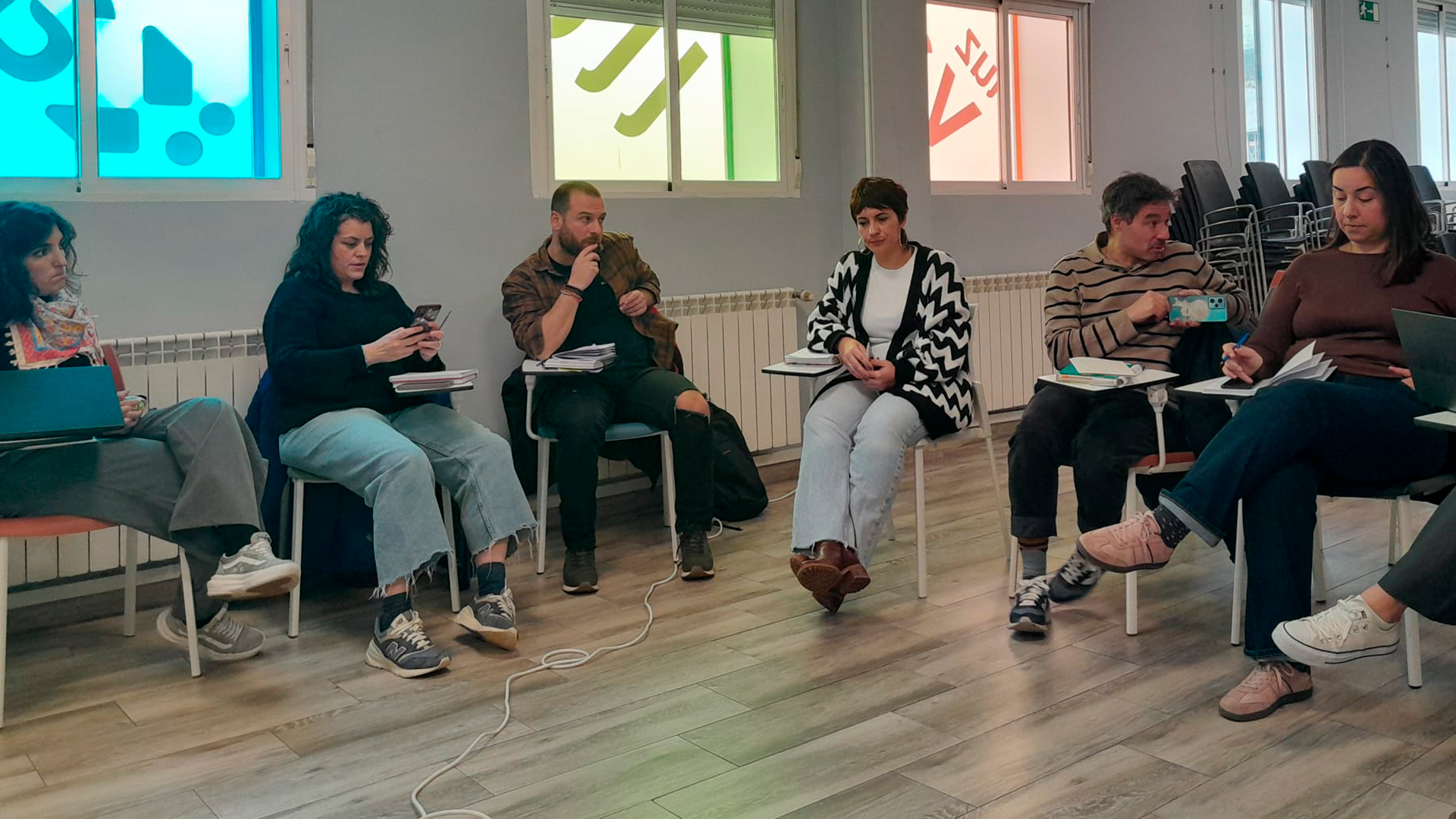 Profesionales de las entidades que participarán del proyecto 'Puentes Vitales', sentados en pupitres en un círculo.