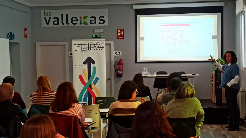 Alumnado de la sesión, de espaldas, atienda a las explicaciones de una de las responsables de la Administración sobre los recursos formativos de la Comunidad de Madrid.