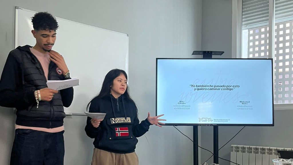Mohamed Halila y Mika Cilindro, de pie al lado de una pantalla de proyección, durante la persentación del proyecto.